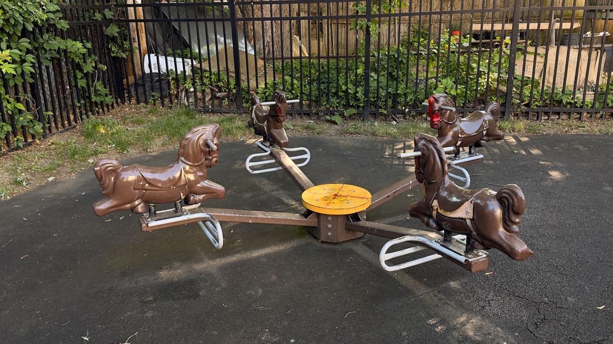 A blue and red plastic rocking horse on a rubber play surface.