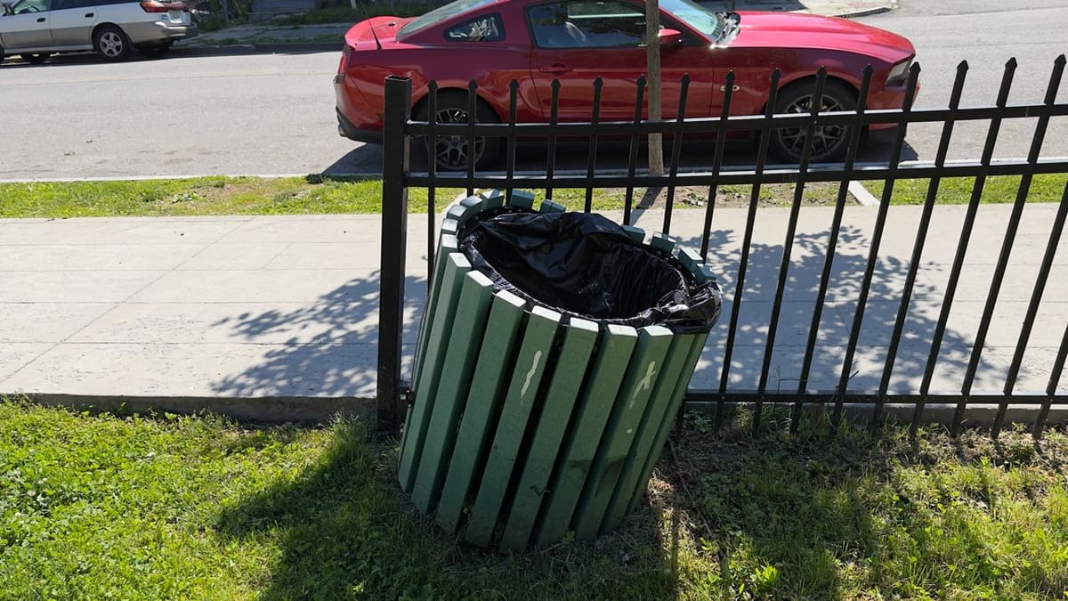 Two black trash receptacles tipped over near the perimeter at Audrey Carey Park.
